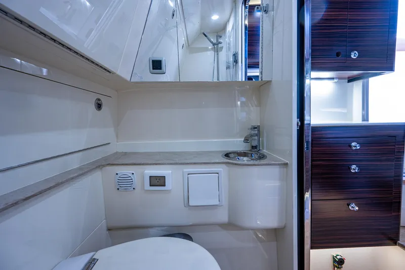 Slide: The Image of 2017 Scout 420 LXF boat bathroom with sink, toilet, and storage cabinets. - 28