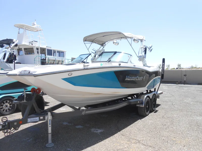 Slide: The Image of 2016 MasterCraft X23 boat on a trailer in a marina. - 1