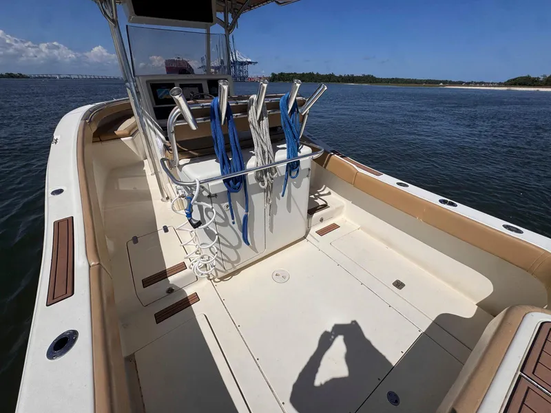 Slide: The Image of 2002 Scout 280 Sportfish boat interior with fishing rod holders on a sunny day. - 10