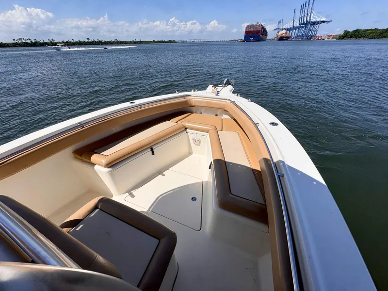 Slide: The Image of 2002 Scout 280 Sportfish boat on calm waters near a port with cranes in the background. - 11
