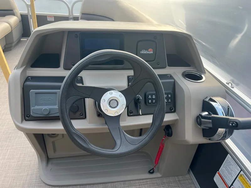 Slide: The Image of 2024 Sun Tracker Party Barge 18 DLX steering console with controls and cup holder. - 2