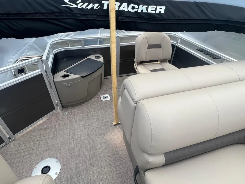Slide: The Image of 2024 Sun Tracker Fishin' Barge 20 DLX interior with beige seating and black accents. - 5