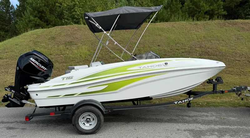 Slide: The Image of 2024 Tahoe T16 boat with green accents on a trailer, parked on a road. - 0