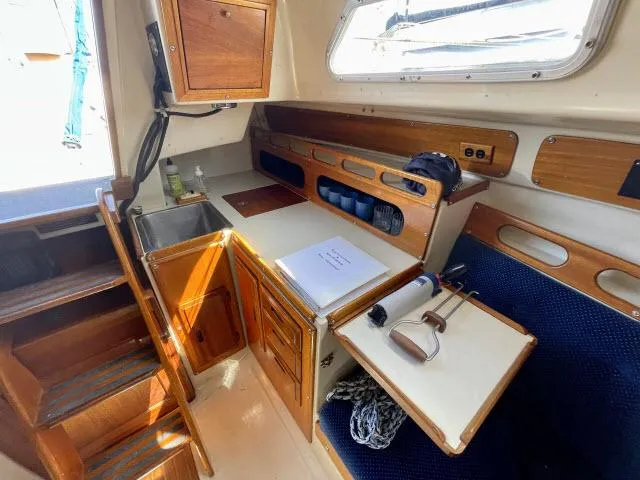 Slide: The Image of Interior of a 1973 Ericson 27 sailboat with wooden cabinetry and compact kitchen. - 4