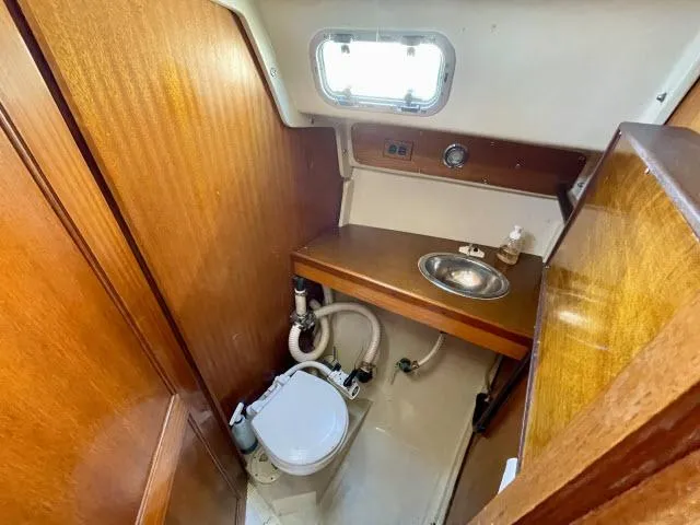 Slide: The Image of 1973 Ericson 27 sailboat bathroom with wooden cabinetry, sink, and toilet. - 8