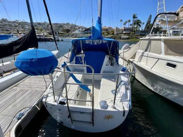 Slide: The Image of 1973 Ericson 27 sailboat docked at a marina, featuring blue covers and a sunny backdrop. - 9