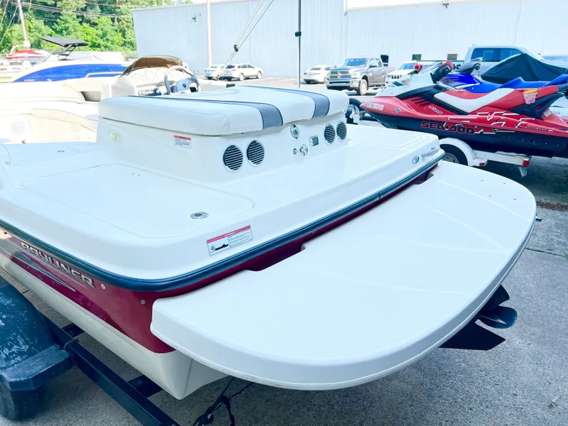 Slide: The Image of 2011 Bayliner 197 boat with swim platform and seating, parked near jet skis. - 11