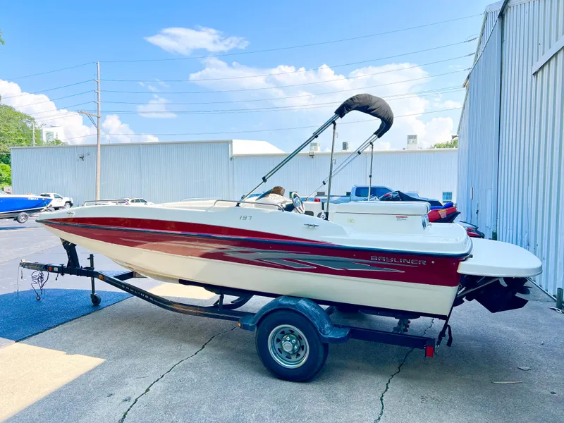 Slide: The Image of 2011 Bayliner 197 boat on trailer, red and white, parked outdoors. - 2