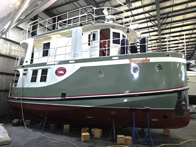 Slide: The Image of 1999 Florida Bay 42 Coaster boat in a warehouse, green and white exterior. - 1