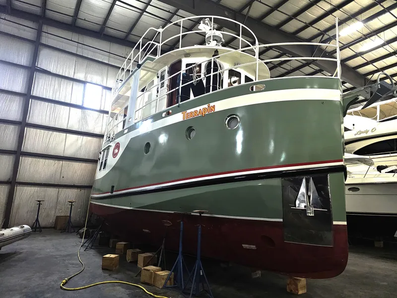Slide: The Image of 1999 Florida Bay 42 Coaster boat in storage, green and white exterior. - 8