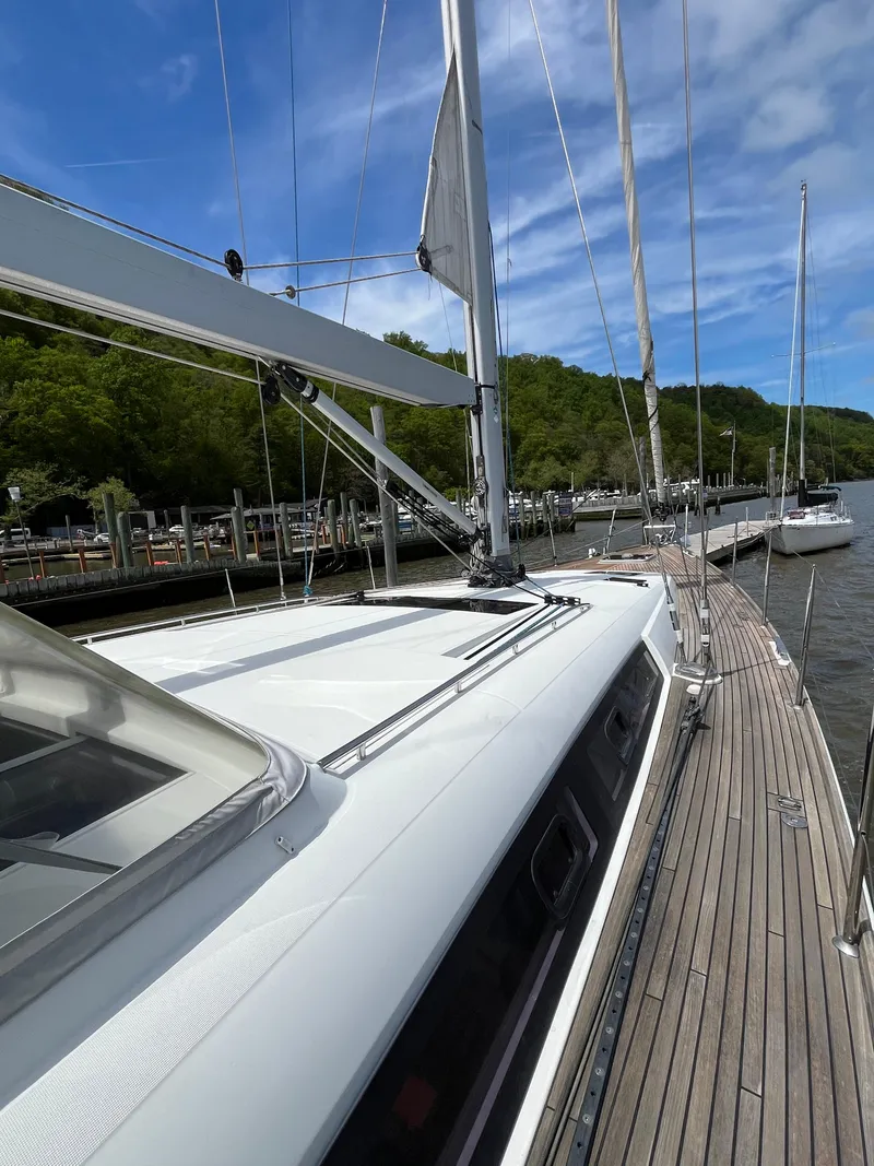 Slide: The Image of 2012 Beneteau Oceanis 58 sailboat docked, showcasing sleek deck and mast under blue sky. - 22