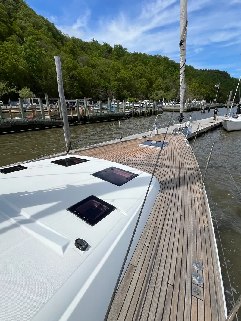 Slide: The Image of Beneteau Oceanis 58 sailboat docked, showcasing sleek deck design and scenic marina backdrop. - 25