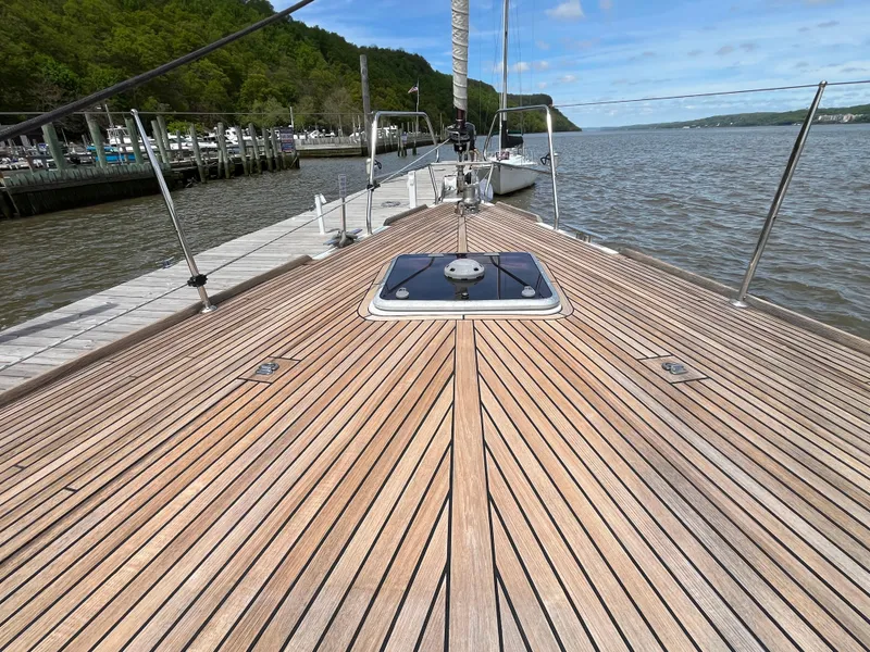 Slide: The Image of Beneteau Oceanis 58 (2012) yacht deck with wooden finish, docked by a scenic river. - 26