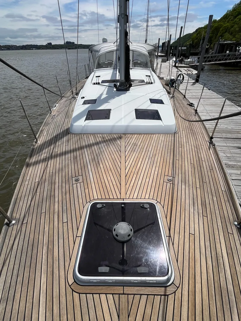 Slide: The Image of 2012 Beneteau Oceanis 58 sailboat with teak deck, docked by the water. - 32