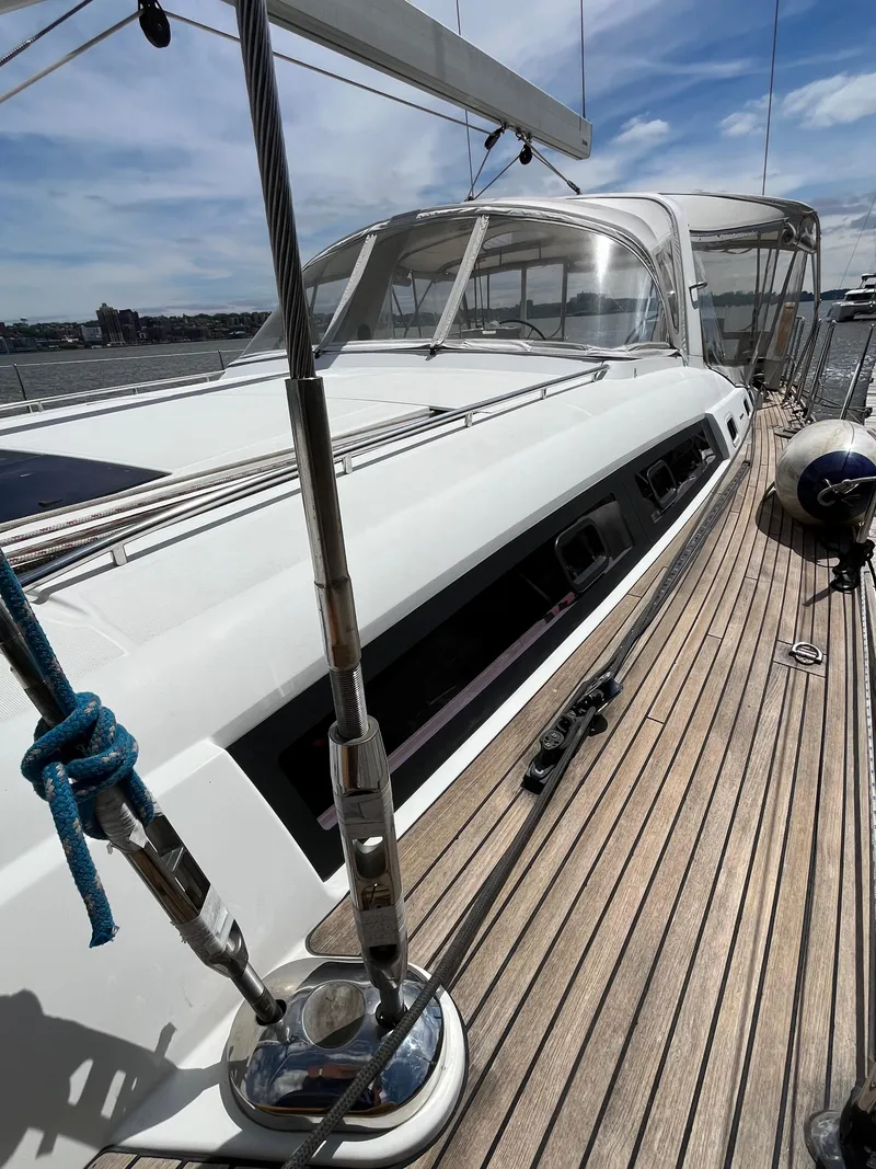 Slide: The Image of 2012 Beneteau Oceanis 58 sailboat deck with clear skies and marina view. - 36