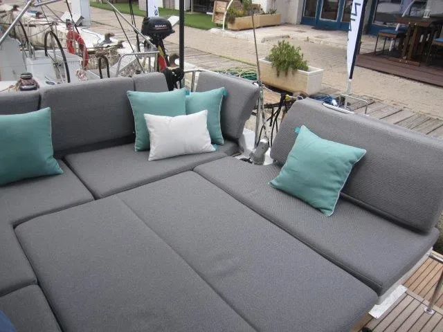Slide: The Image of Jeanneau 55 2024 yacht with spacious gray cushioned seating and teal pillows. - 13