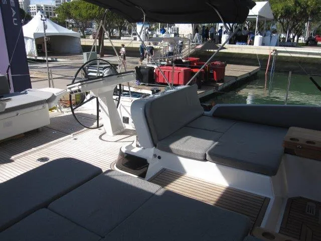 Slide: The Image of 2025 Jeanneau Yacht 65 deck with seating and steering wheel at marina. - 21