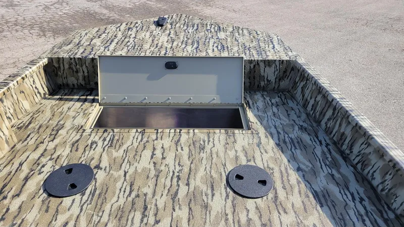 Slide: The Image of 2025 Smoker Craft Sportsman 1866 camo boat interior with storage compartment open. - 13