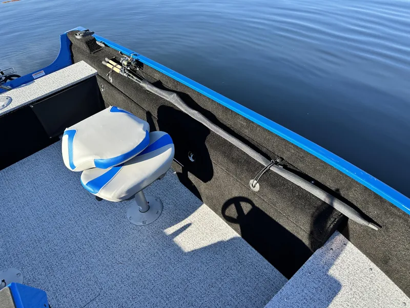 Slide: The Image of 2025 Smoker Craft Lazer 161 side console boat interior with blue and gray seating. - 18