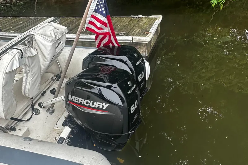 Slide: The Image of 2003 Novurania 530 DL with twin Mercury 60 outboard engines docked by a wooden pier. - 3