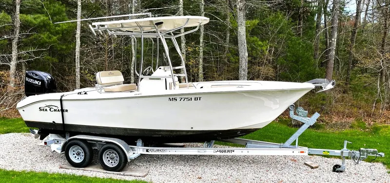 The Image of 2022 Sea Chaser 22 HFC boat on trailer, parked on gravel, surrounded by trees. - 0