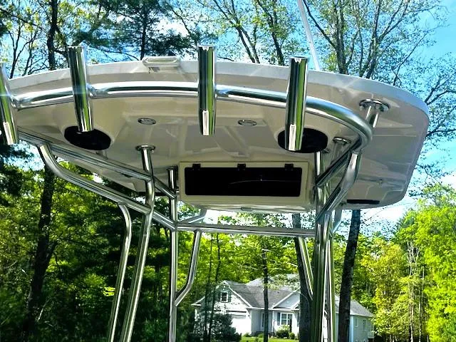 Slide: The Image of 2022 Sea Chaser 22 HFC boat with T-top and rod holders, surrounded by trees. - 4