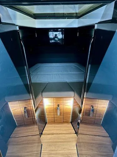 Slide: The Image of 2024 XO Boats EXPLR 10S cabin interior with modern wood finish and cozy sleeping area. - 5
