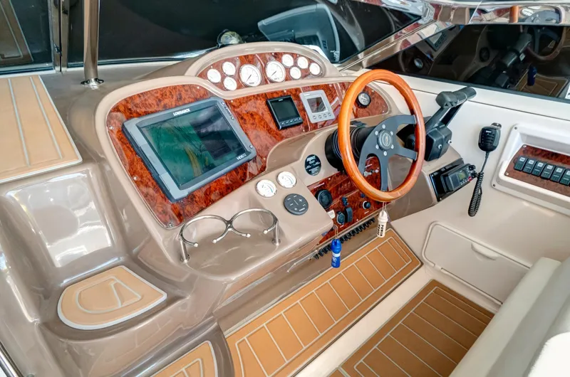 Slide: The Image of 2006 Regal 3560 Commodore boat cockpit with modern navigation instruments and wooden steering wheel. - 15