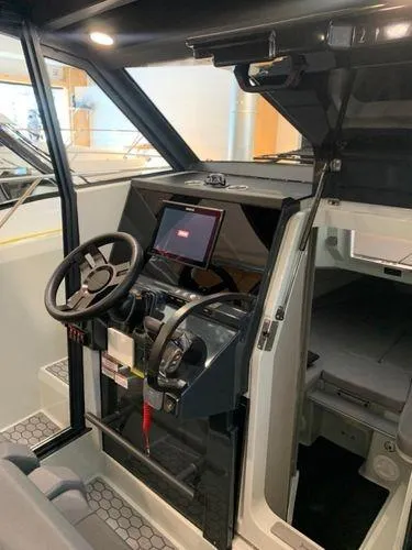 Slide: The Image of 2024 XO Boats DFNDR 9 cockpit with steering wheel and navigation system. - 2