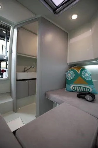 Slide: The Image of 2024 XO Boats DFNDR 9 interior cabin with seating, pillow, and kitchenette. - 4