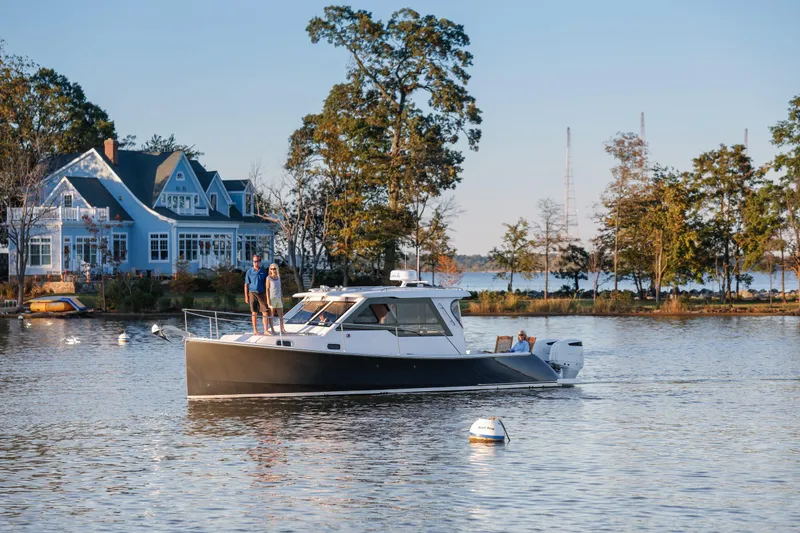 Slide: The Image of 2024 True North 34 boat cruising near a lakeside house. - 21