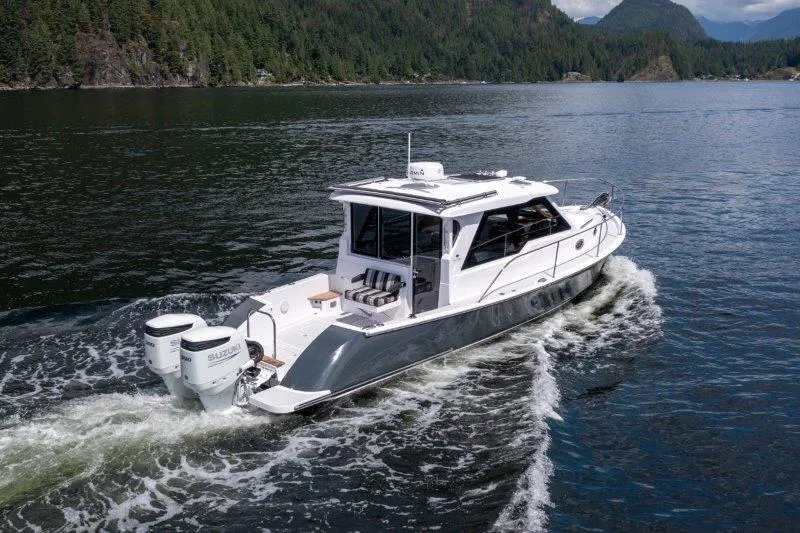 Slide: The Image of 2024 True North 34 boat cruising on a scenic lake with forested hills. - 24