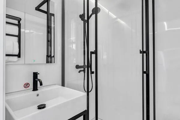 Slide: The Image of Modern bathroom with La Mare Modern 11 shower, black fixtures, and white sink, 2024 model. - 16