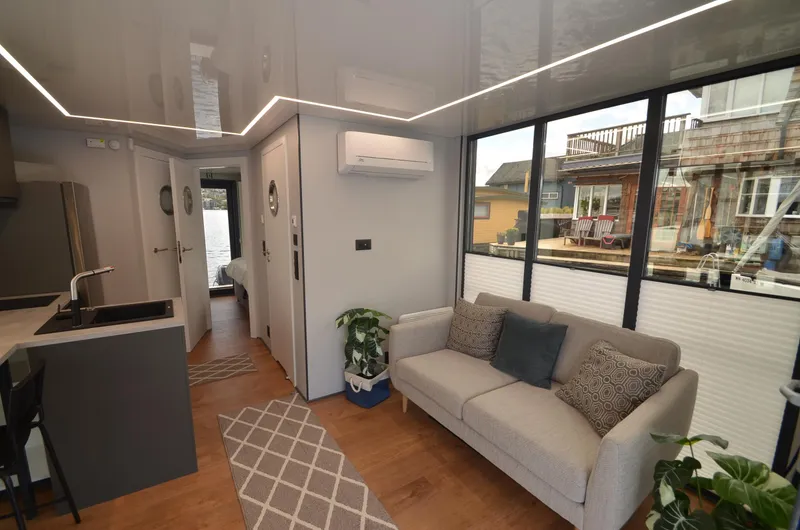 Slide: The Image of Modern La Mare 2024 houseboat interior with sleek design, cozy sofa, and large windows. - 3