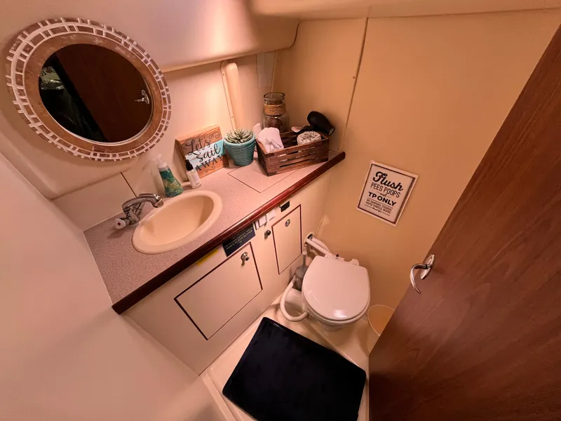 Slide: The Image of Compact bathroom in a 2005 Hunter 31 boat, featuring a sink, toilet, and mirror. - 20