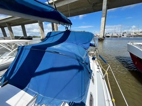 Slide: The Image of 2005 Hunter 31 sailboat with blue canopy docked under a bridge. - 5