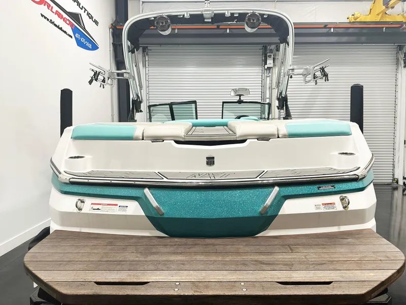 Slide: The Image of 2020 MasterCraft NXT 22 boat in showroom, rear view with teal accents. - 3