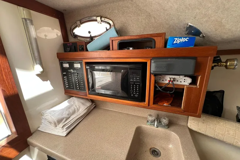 Slide: The Image of 2002 Albemarle 285 Express Fisherman cabin with microwave, sink, and storage shelves. - 11