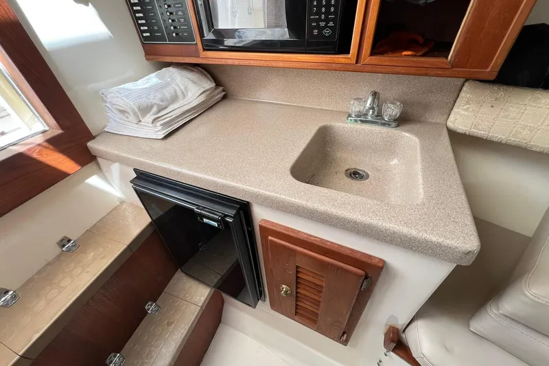 Slide: The Image of 2002 Albemarle 285 Express Fisherman galley with sink, microwave, and compact fridge. - 12