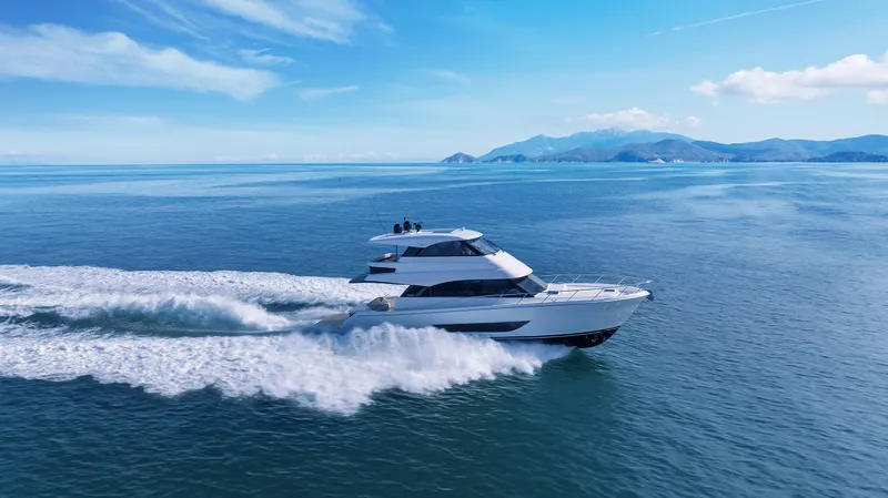 Slide: The Image of 2026 Maritimo M55 yacht cruising on open sea with scenic mountain backdrop. - 2