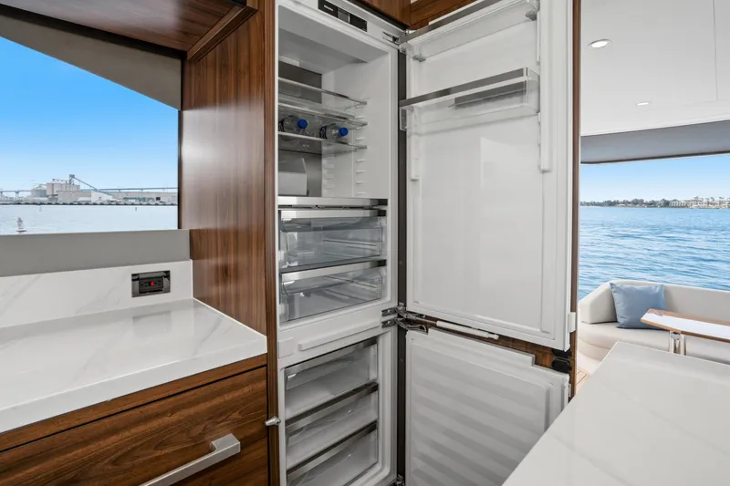 Slide: The Image of Luxury Maritimo M55 yacht kitchen with open fridge, overlooking serene waterfront view. - 58