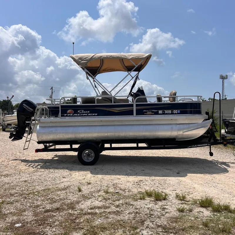 Slide: The Image of 2023 Sun Tracker Party Barge 18 DLX pontoon boat on trailer under a cloudy sky. - 6