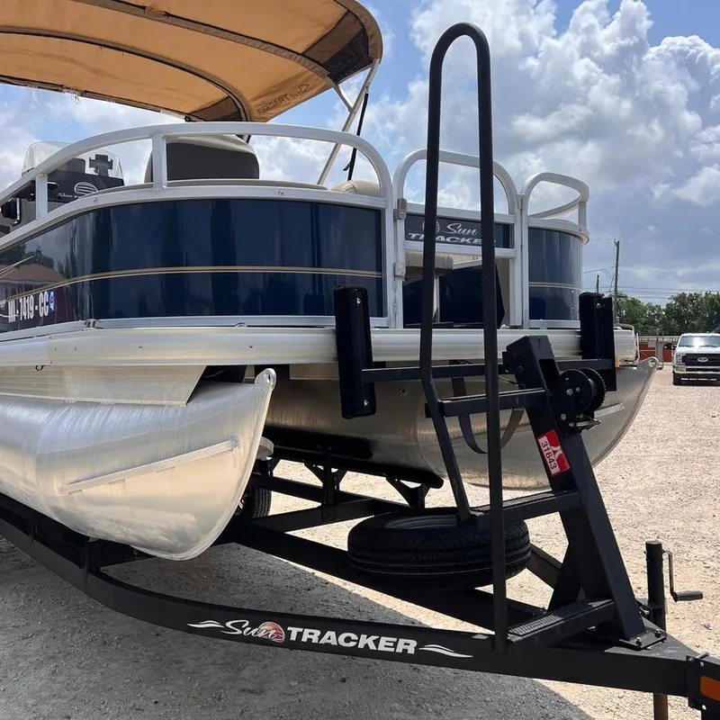 Slide: The Image of 2023 Sun Tracker Party Barge 18 DLX pontoon boat on trailer under a cloudy sky. - 7