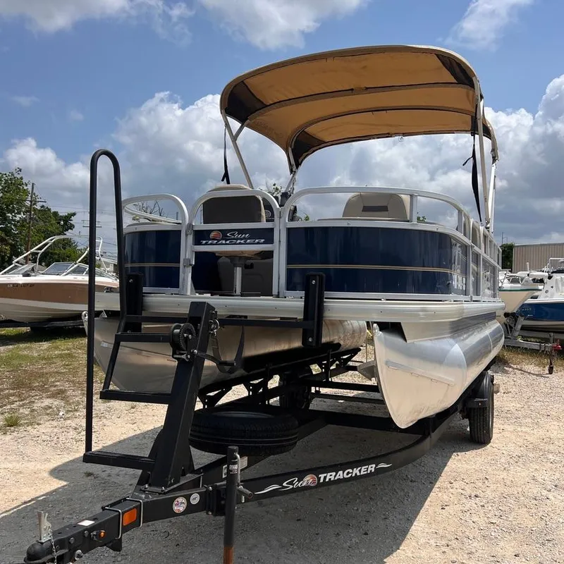 Slide: The Image of 2023 Sun Tracker Party Barge 18 DLX pontoon boat on trailer, blue and white, with canopy. - 8