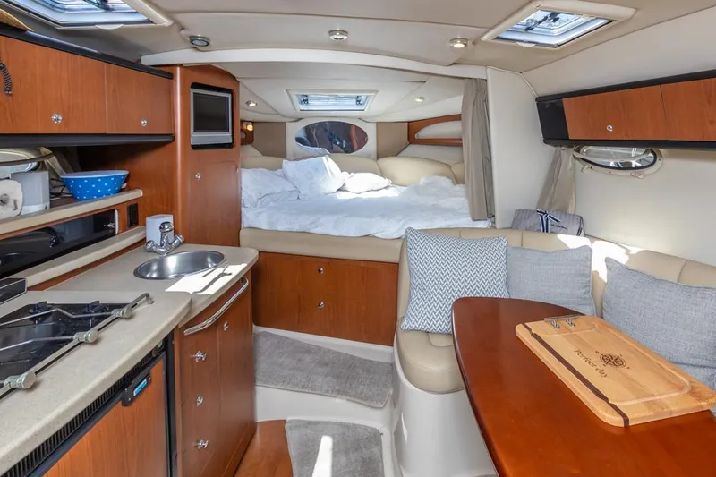 Slide: The Image of Interior of 2004 Chaparral Signature 310 boat with cozy bed, kitchenette, and dining area. - 19