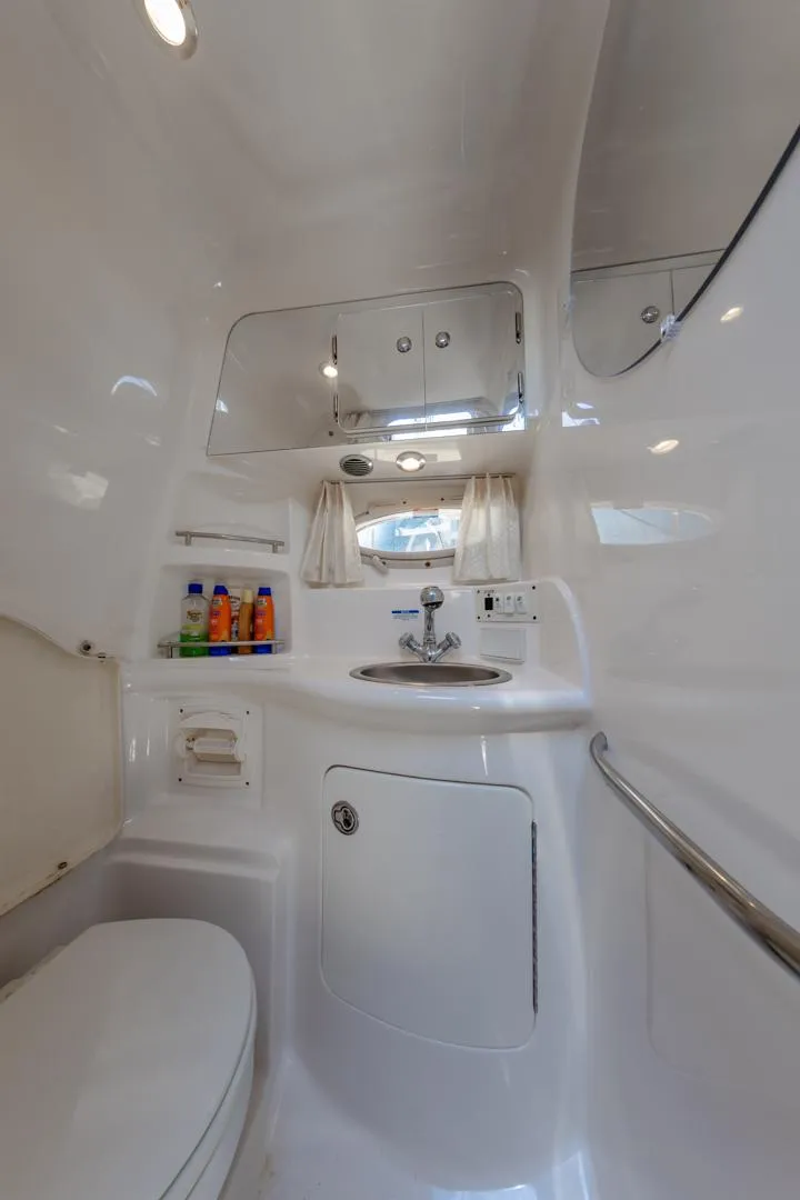 Slide: The Image of 2004 Chaparral Signature 310 boat bathroom with sink, mirror, and storage cabinets. - 23
