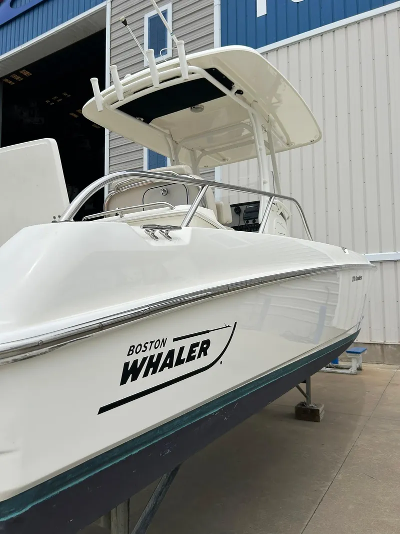 Slide: The Image of 2017 Boston Whaler 270 Dauntless boat, white hull, docked near a blue and gray building. - 5