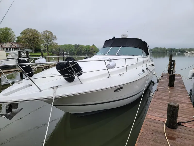 Slide: The Image of 2000 Cruisers 3870 Express yacht docked on a calm lake. - 2