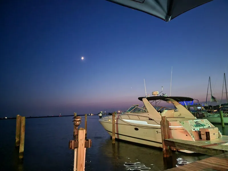 Slide: The Image of 2000 Cruisers 3870 Express yacht docked at sunset with a crescent moon. - 23