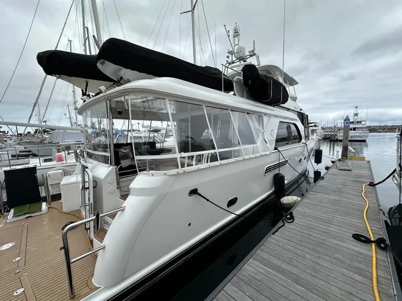 Slide: The Image of 1999 Queenship Cockpit Motoryacht docked at a marina on a cloudy day. - 1